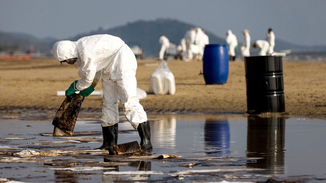 Workers clean up crude oil on Mae Ram Phueng beach following a spill caused by a leak in an undersea pipeline owned by Star Petroleum Refining Public Company Limited (SPRC) in Rayong on January 29, 2022. 
