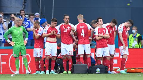 Los jugadores de Dinamarca se ven abatidos cuando su compañero Christian Eriksen (oculto) recibe tratamiento médico durante el partido de la Eurocopa 2020 contra Finlandia.