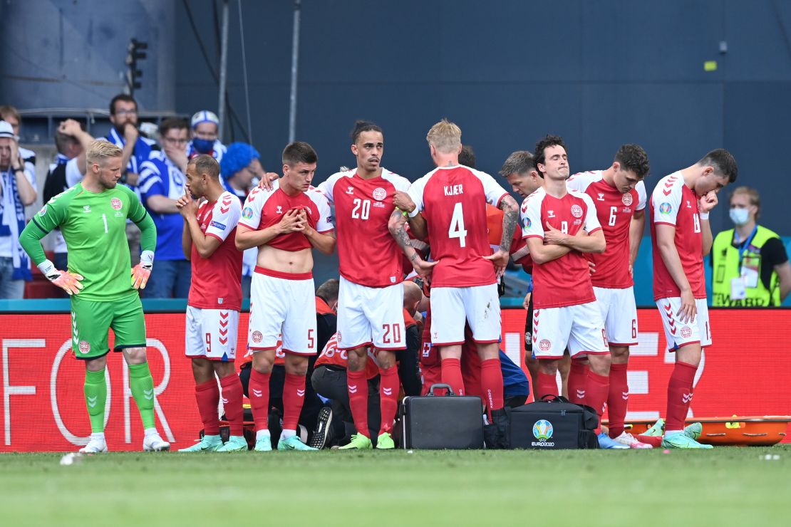 Denmark's players look dejected as teammate Christian Eriksen (hidden) receives medical treatment during the Euro 2020 match against Finland.