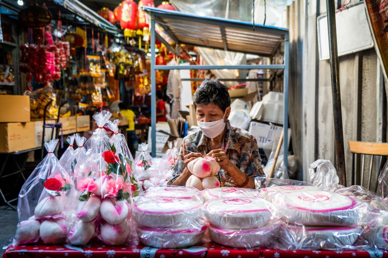 A woman packages homemade Chinese desserts at a market in Bangkok, Thailand.