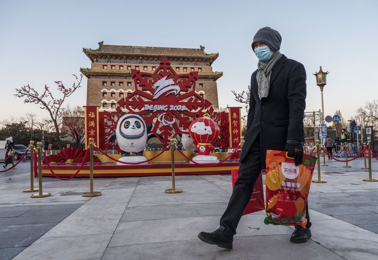 A man walks past a display promoting the Winter Olympics in front of the historic Qianmen Gate in Beijing.