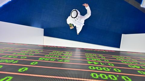 A trader walks beneath a stock display board at the Dubai Stock Exchange.