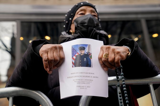 A woman holds a program for Mora's funeral.