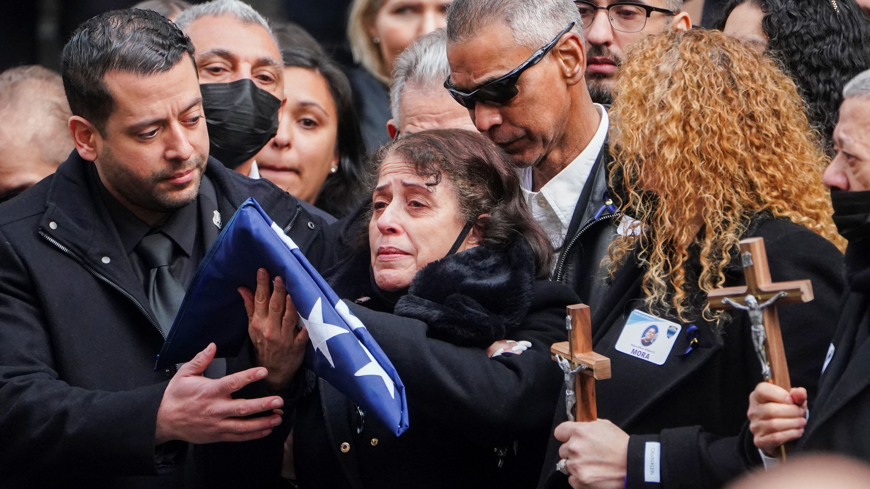 Mora's mother holds a flag from his casket.