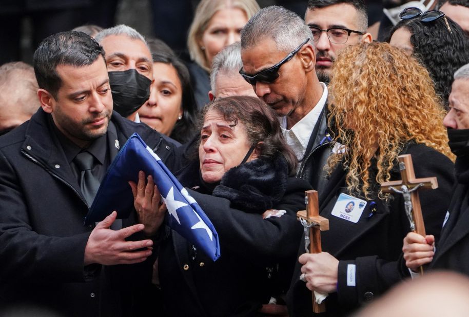 Mora's mother holds a flag from his casket.