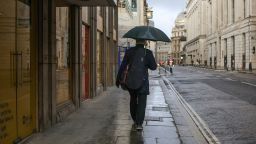 A morning commuter carrying an umbrella while walking through the City of London, U.K., on Tuesday, Jan. 4, 2022. 