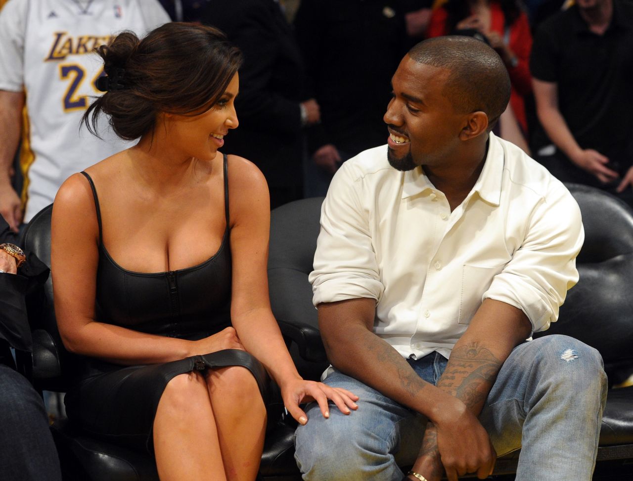West and Kim Kardashian talk from their courtside seats at an NBA playoff game in 2012. They married in 2014.