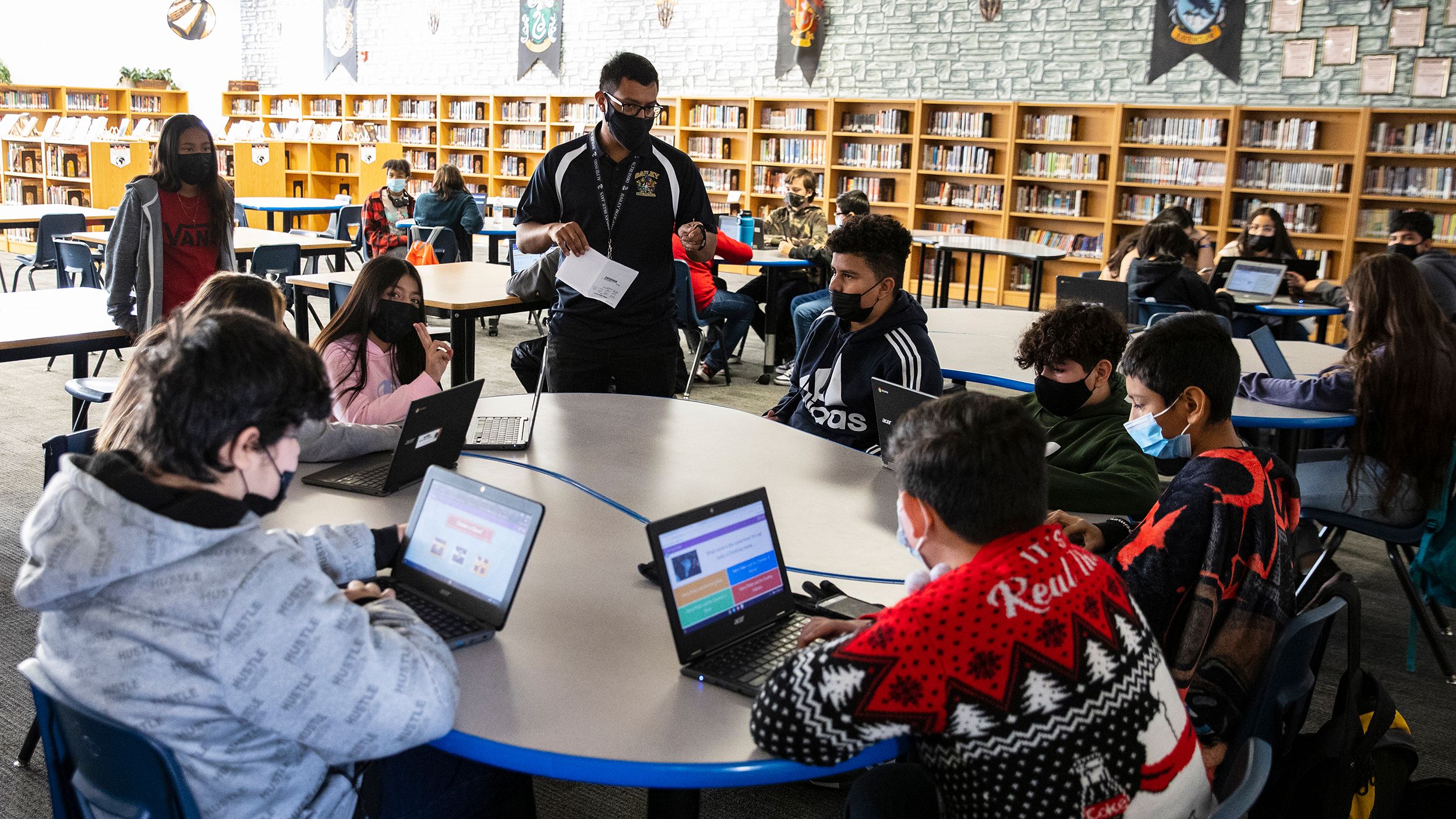 A substitute teacher at a Las Vegas middle school works with three classes of students at the school library in December 2021.