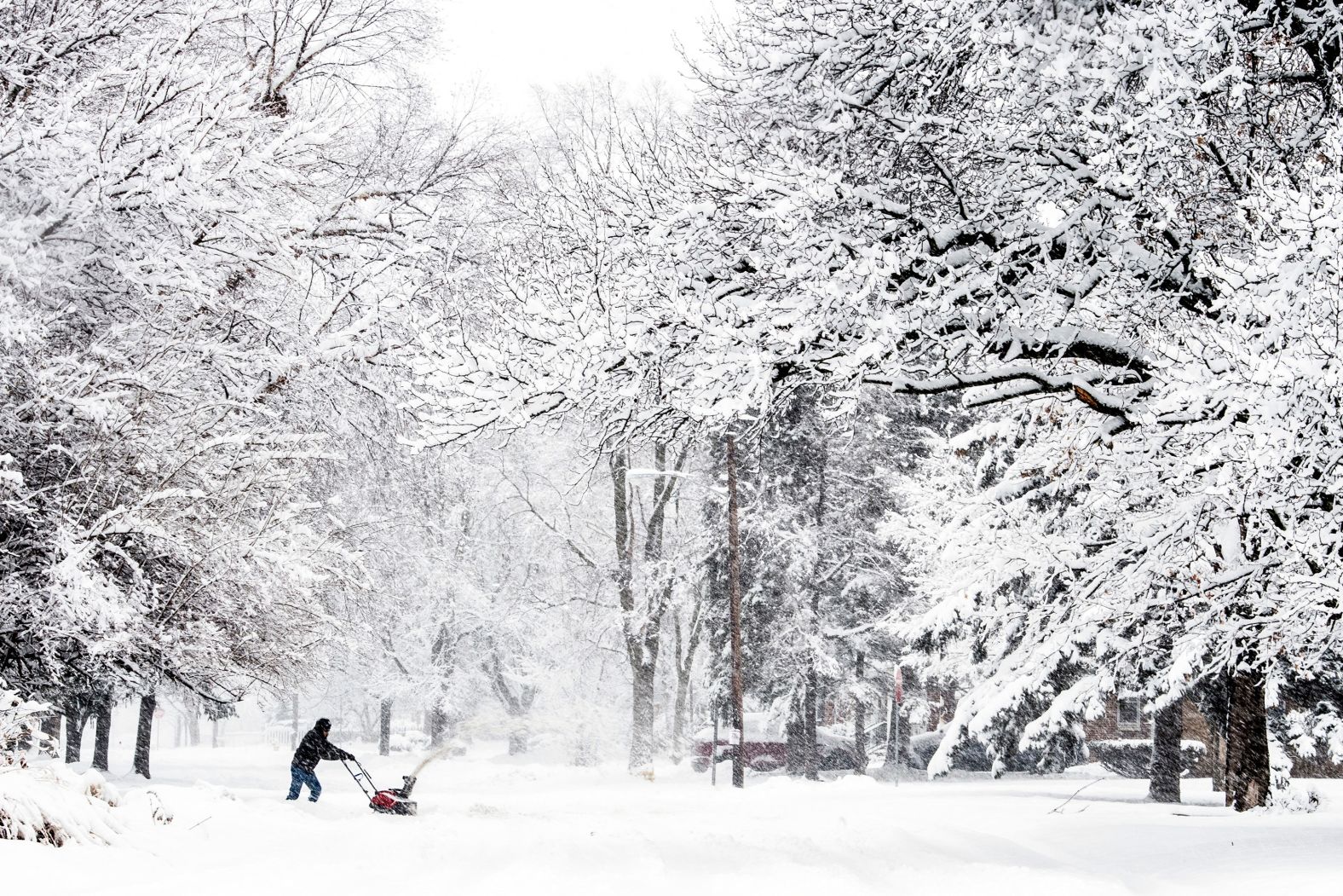 Cory Pacheco uses a snow blower to clear out his driveway in Flint, Michigan.