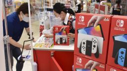 A man buys the new model of the Nintendo Switch game console at an electric appliance store in Osaka, western Japan, on Oct. 8, 2021, its launch day. 