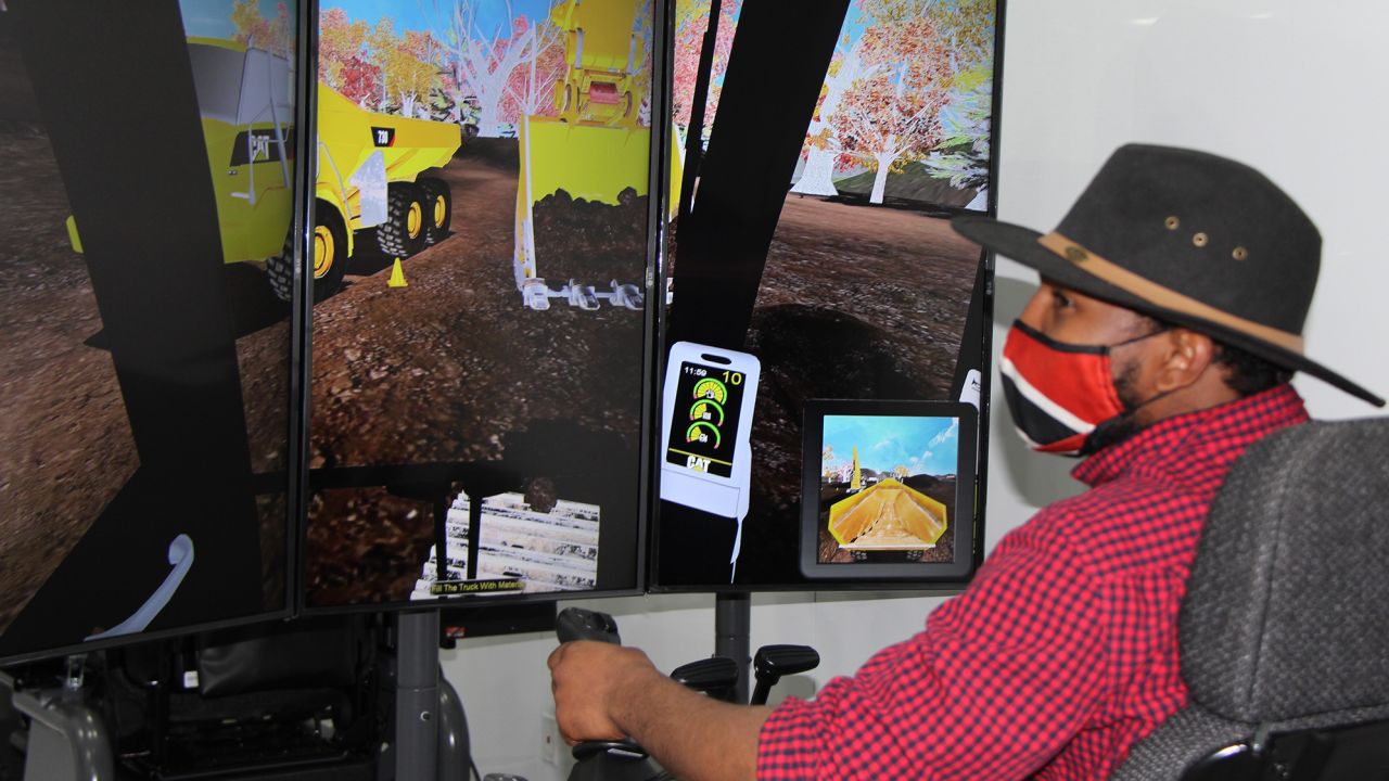Using simulation equipment, a prospective student at Blue Ridge Community College in Virginia tries loading rocks using a backhoe.