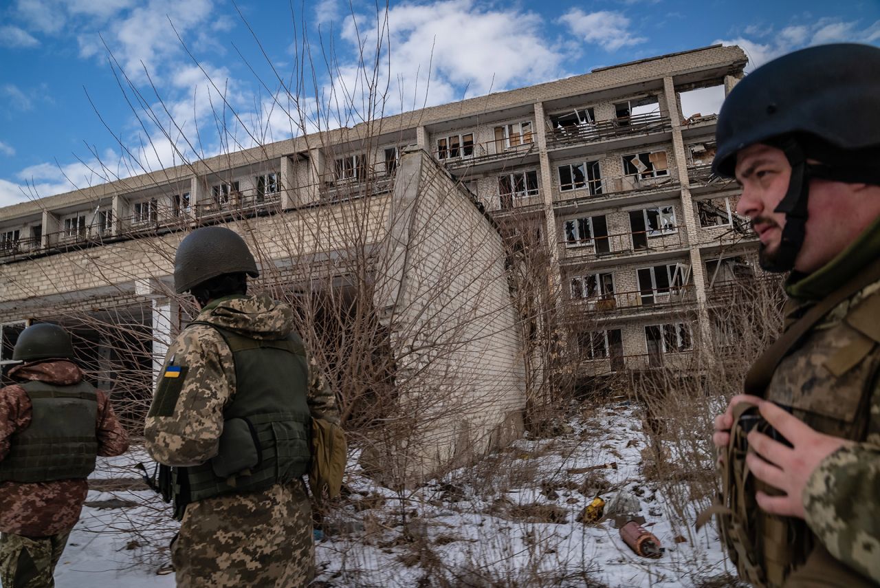 Ukrainian soldiers walk past a destroyed building in Marinka.