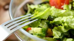 Silver fork in a plate of mixed salad