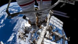 This view from NASA spacewalker Thomas Marshburn's camera points toward his U.S. spacesuit legs, downward from the Canadarm2 robotic arm that he is attached to, and toward the International Space Station below him on December 2, 2021. The station's prominent features include (from left) the Kibo laboratory module's external pallet, the truss structure, its radiators, and the orbiting lab's Russian segment.