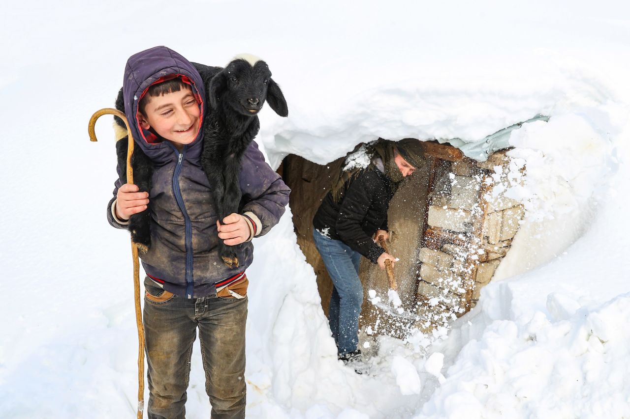 A child carries a goat in front of his snow-covered house in Van, Turkey, on Saturday, January 29.