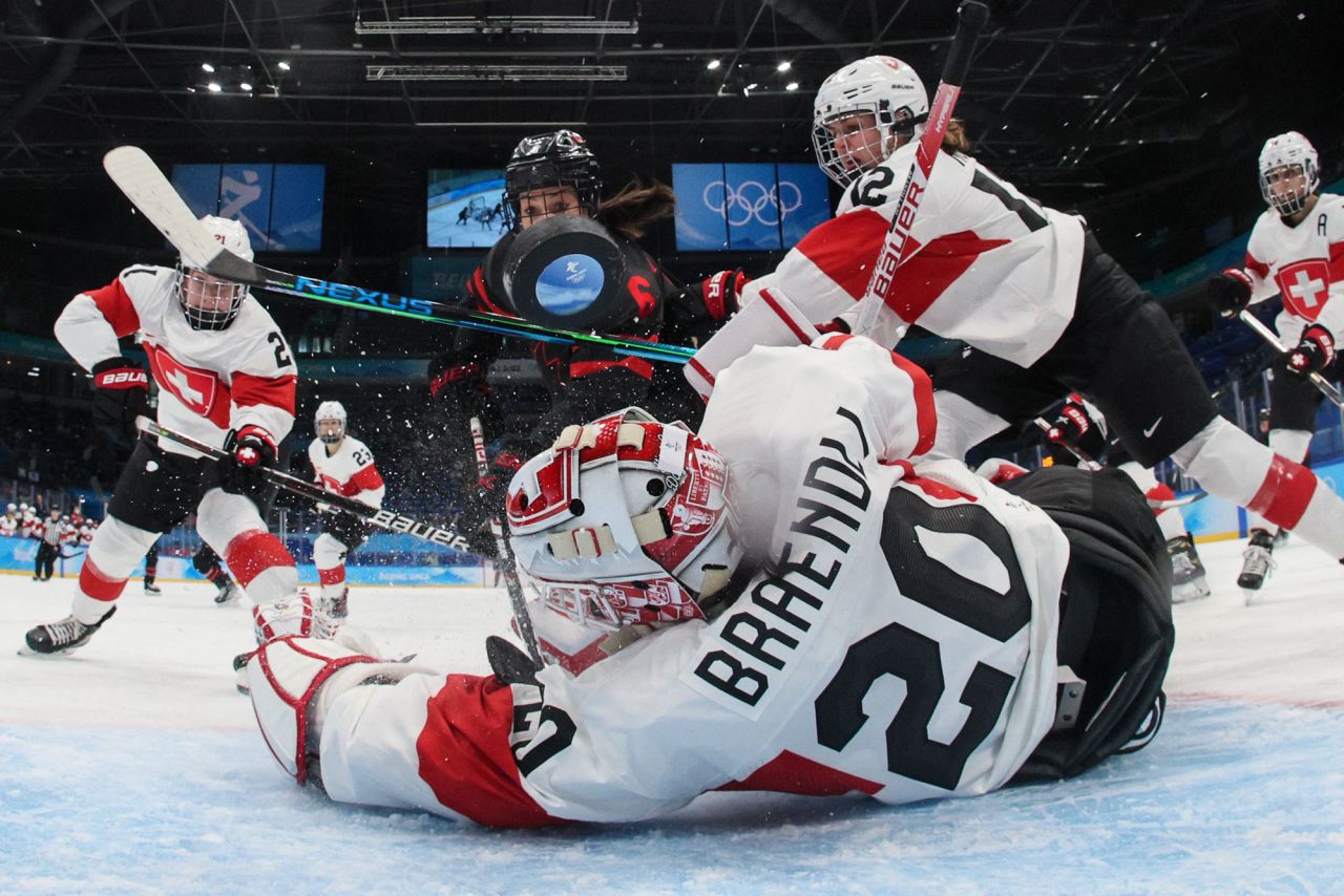 Canada's Rebecca Johnston, center, scores a goal against Switzerland during a preliminary hockey game on February 3. The Canadians won 12-1.