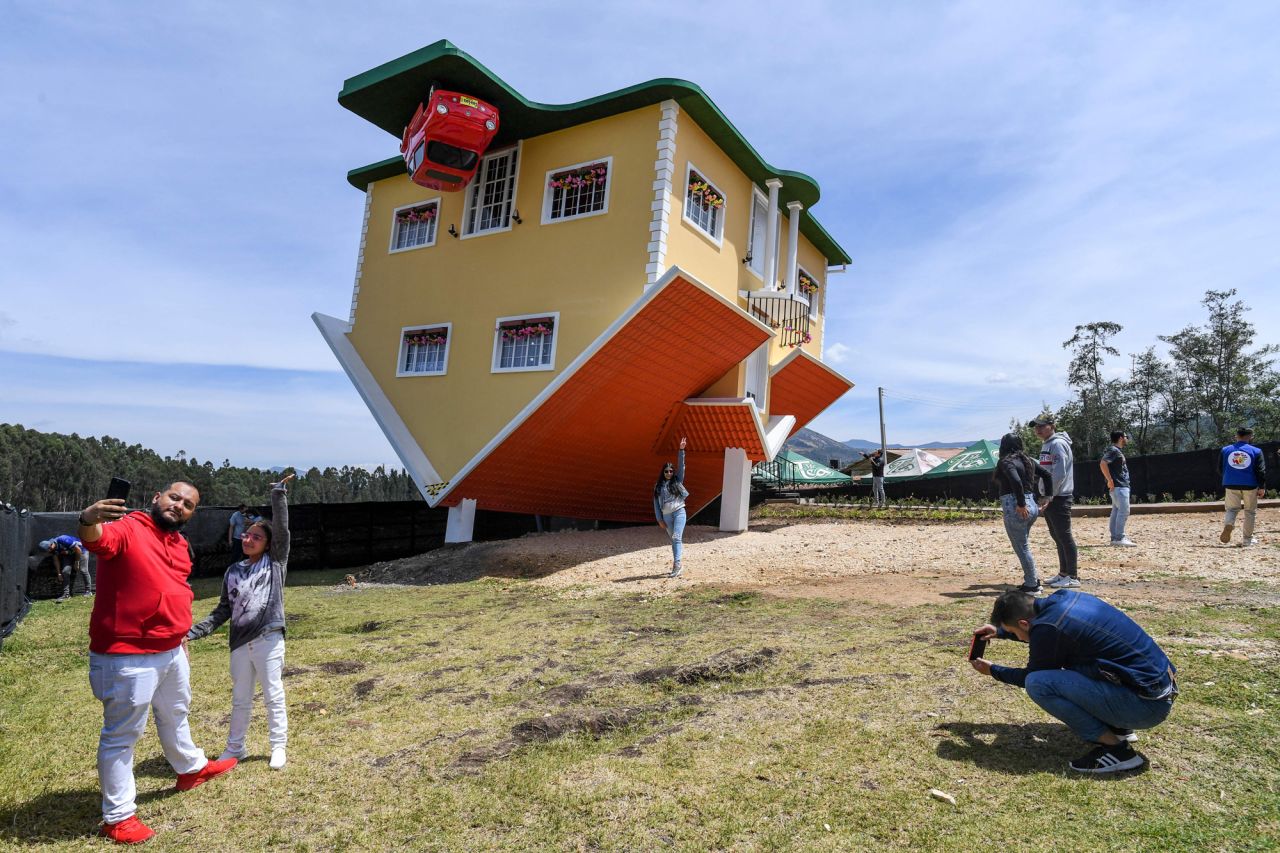 People pose for photos outside an upside-down house in Guatavita, Colombia, on Saturday, January 29. The house was designed by its Austrian owner, Fritz Schall.