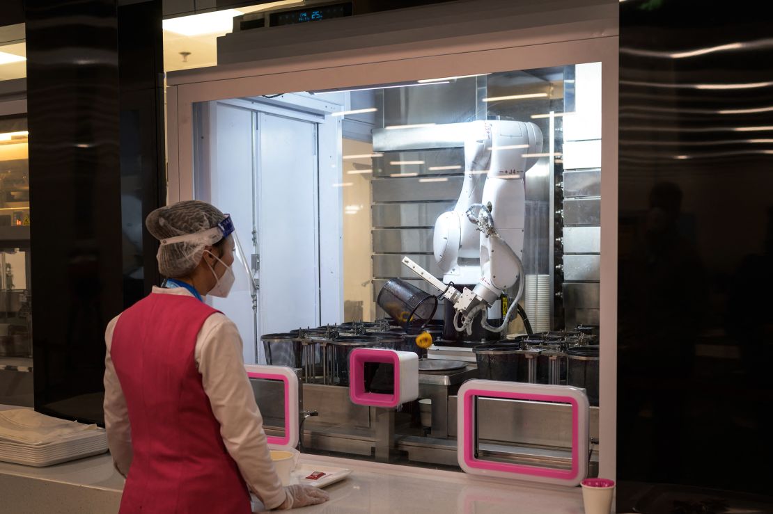 A worker waits for a robot processing an order at the dining hall of the Main Press Center of the 2022 Winter Olympics in Beijing.