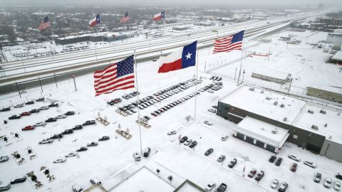 Flags fly over car dealerships as light traffic moves through snow and ice on Route 183 in Irving, Texas, on February 3.