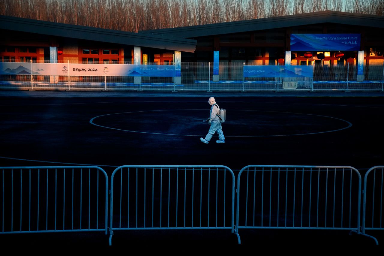 A worker wearing a protective suit sprays disinfectant at a screening checkpoint for arriving athletes on February 1.