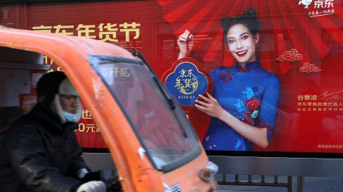 A delivery worker rides pasts an advertisement showing Eileen Gu, at a bus stop in Beijing on January 11.