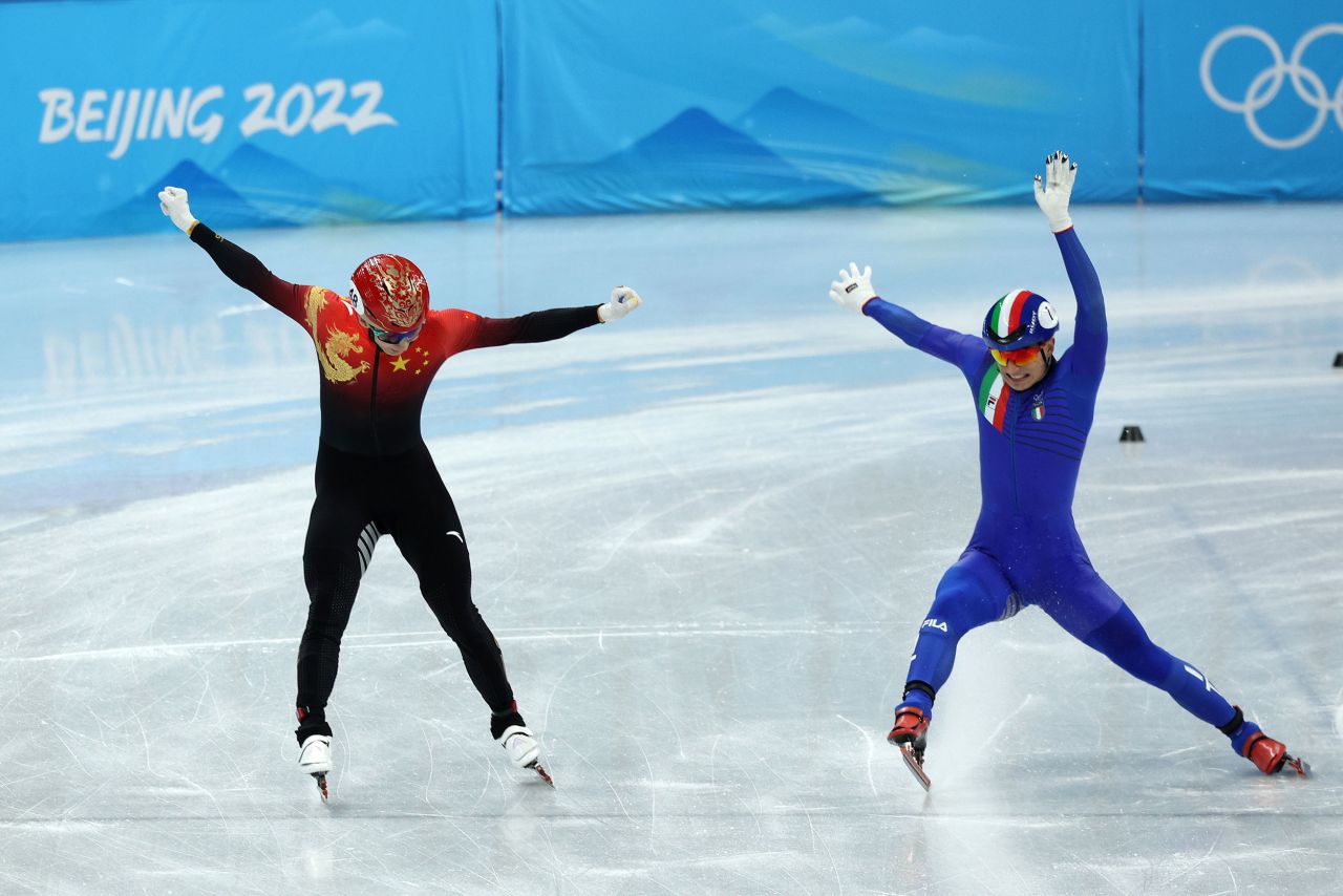 China's Wu Dajing, left, narrowly beats out Italy's Pietro Sighel to win the short track mixed relay on February 5. It was the host nation's first gold medal of these Games.