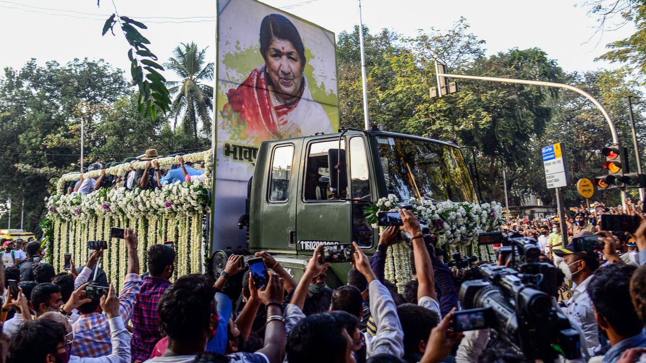 People gather to catch a glimpse of the funeral procession of late Bollywood singer Lata Mangeshkar who died in Mumbai on February 6, 2022.