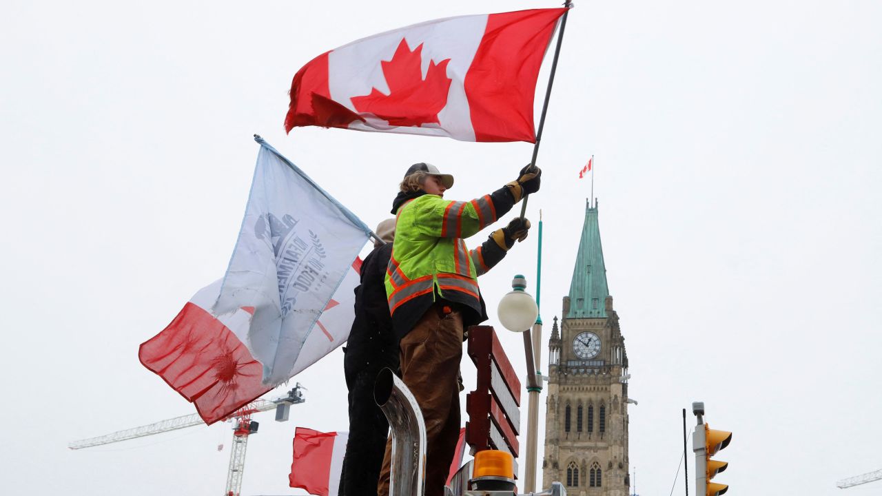 People wave flags on top of a truck in front of Parliament Hill in Ottawa on February 6.