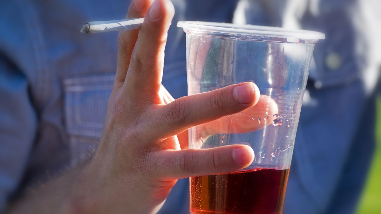 A person drinks an alcoholic beverage while smoking cannabis. Adults who reported using cannabis and alcohol also said they drove under the influence of these drugs, a new study found. 