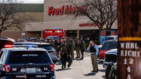Emergency responders gather at the store as the hunt for a suspect continued Monday.