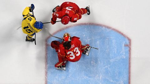 China's goaltender Zhou Jiaying (bottom) and teammate Yu Baiwei defend their goal from Sweden's Lisa Johansson during their women's preliminary round group B match at the Beijing 2022 Winter Olympic Games.