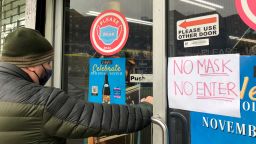 Man entering store with a No Mask, No Entry sign on door, Queens, New York. (Photo by: Lindsey Nicholson/UCG/Universal Images Group via Getty Images)