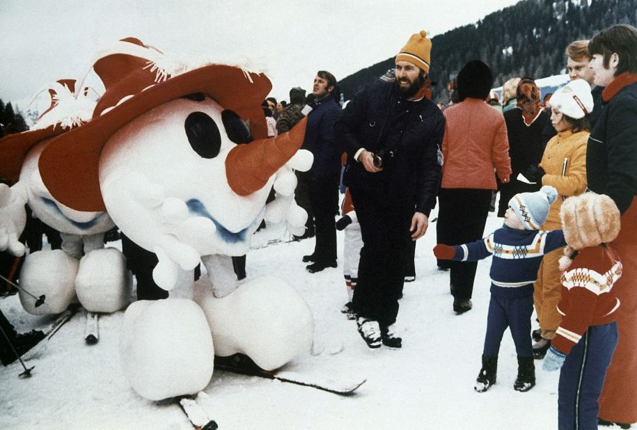 A snowman, mascot of the 1976 Winter Olympics in Innsbruck, greets children in Kitzbuhel, Austria, during the world downhill ski events, January 1975. 