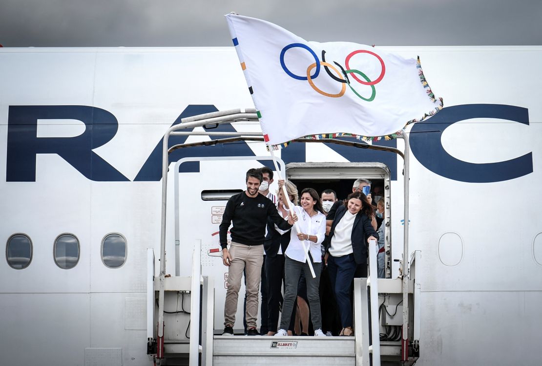 President of the Paris 2024 Organizing Committee Tony Estanguet (L) and Paris mayor Anne Hidalgo (C) wave the Olympic flag to mark the handover.