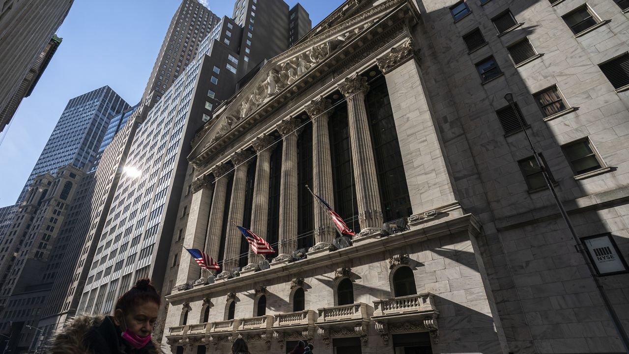 Pedestrians walk past the New York Stock Exchange, Jan. 24 in New York.