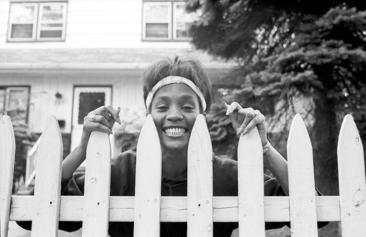 Whitney Houston looks over the picket fence of her mother's home in West Orange, New Jersey, on May 28, 1985.