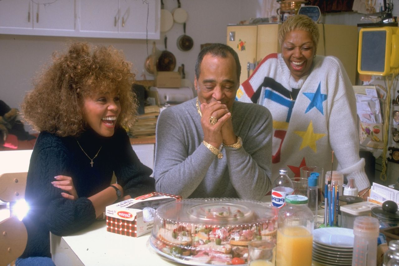 Whitney Houston, left, sits with her mother, Cissy, and her father, John, at the kitchen table at home.