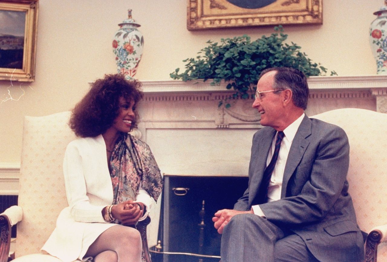 Whitney Houston sits with President George H. W. Bush in the Oval Office.