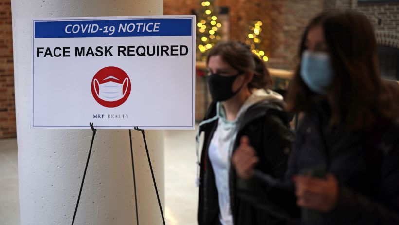 WASHINGTON, DC - DECEMBER 21:  People pass a sign that reads "Face Mask Required" in a mall as COVID-19 cases surge in the city on December 21, 2021 in Washington, DC. District of Columbia Mayor Muriel Bowser reinstated the city's indoor mask mandate at 6am on Tuesday and announced a vaccination mandate for government employees after COVID-19 case numbers have surged to a new high.  (Photo by Alex Wong/Getty Images)