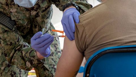 Hospital Corpsman 3rd Class Joseph Casassa administers a Covid-19 vaccine to Logistics Specialist Seaman Rix Zhang. 