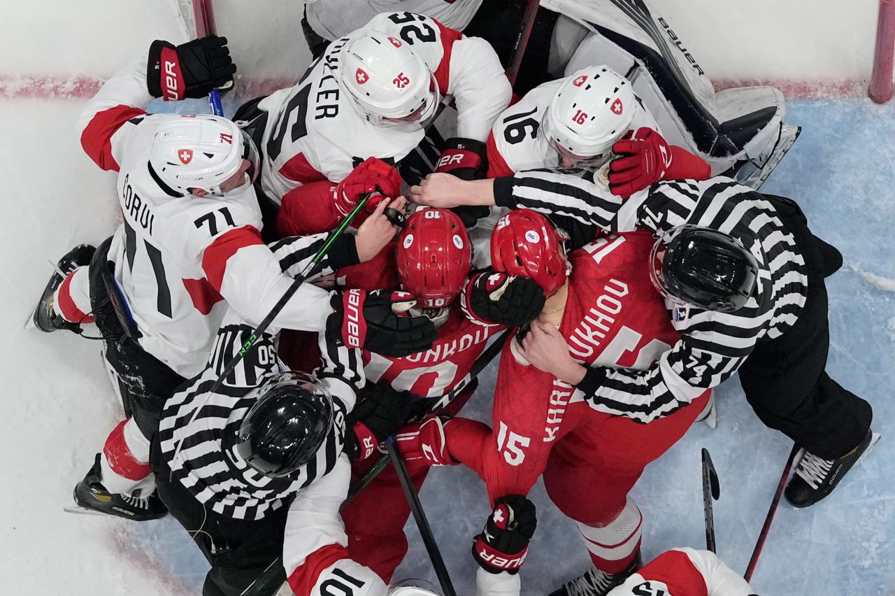 Officials try to separate hockey players from Switzerland (white helmets) and the Russian Olympic Committee during a goalmouth scrum on February 9. It was the first game of the men's hockey tournament.