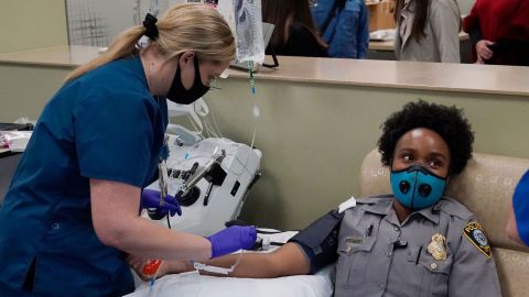 Oklahoma City police officer Erica Jackson looks away as phlebotomist Ashley Jones prepares to take her blood for a convalescent plasma donation. 