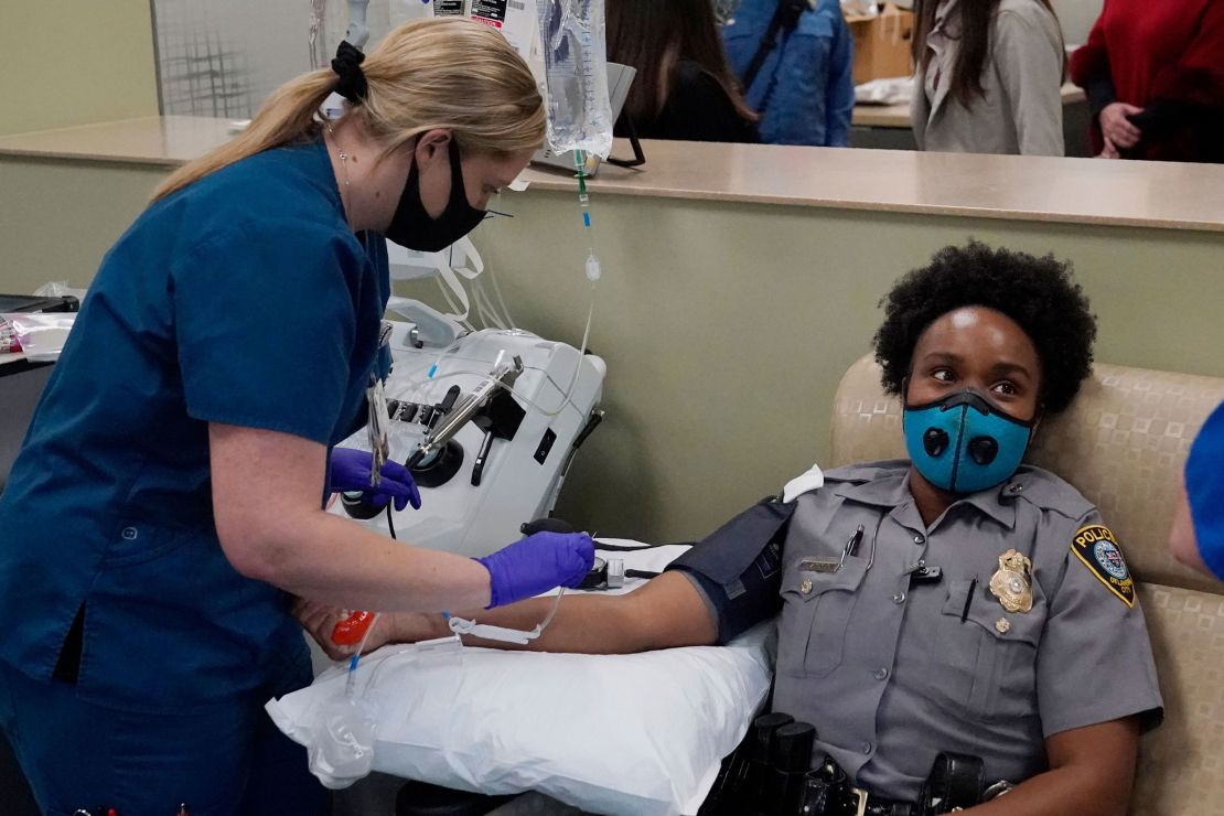 Oklahoma City police officer Erica Jackson looks away as phlebotomist Ashley Jones prepares to take her blood for a convalescent plasma donation. 