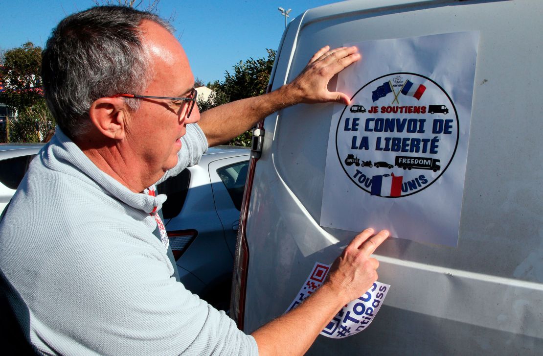 A man puts a poster reading "Liberty Convoy" on a van before departing for Paris, in Bayonne, southwest France, on Wednesday.