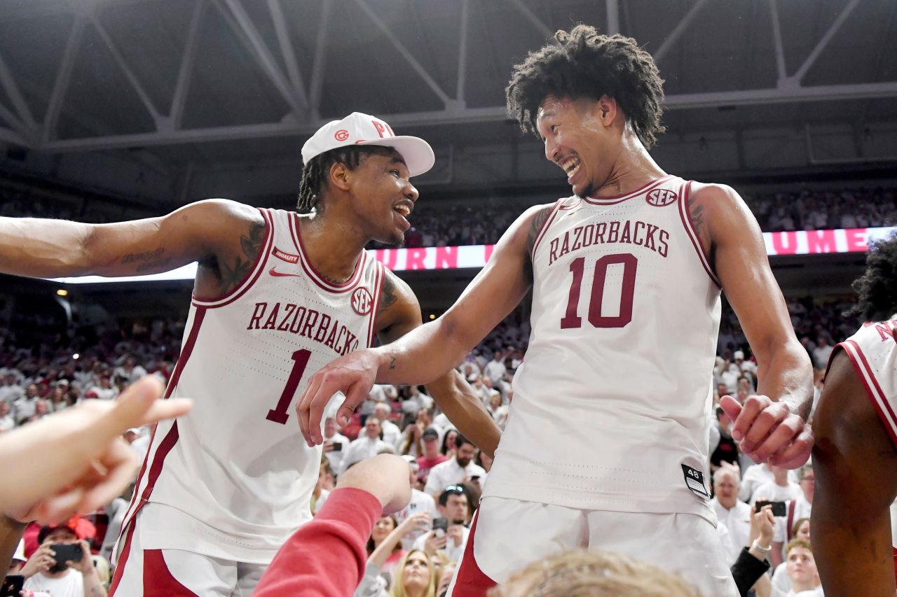 Arkansas basketball players JD Notae, left, and Jaylin Williams celebrate with fans after the Razorbacks upset top-ranked Auburn on Tuesday, February 8.