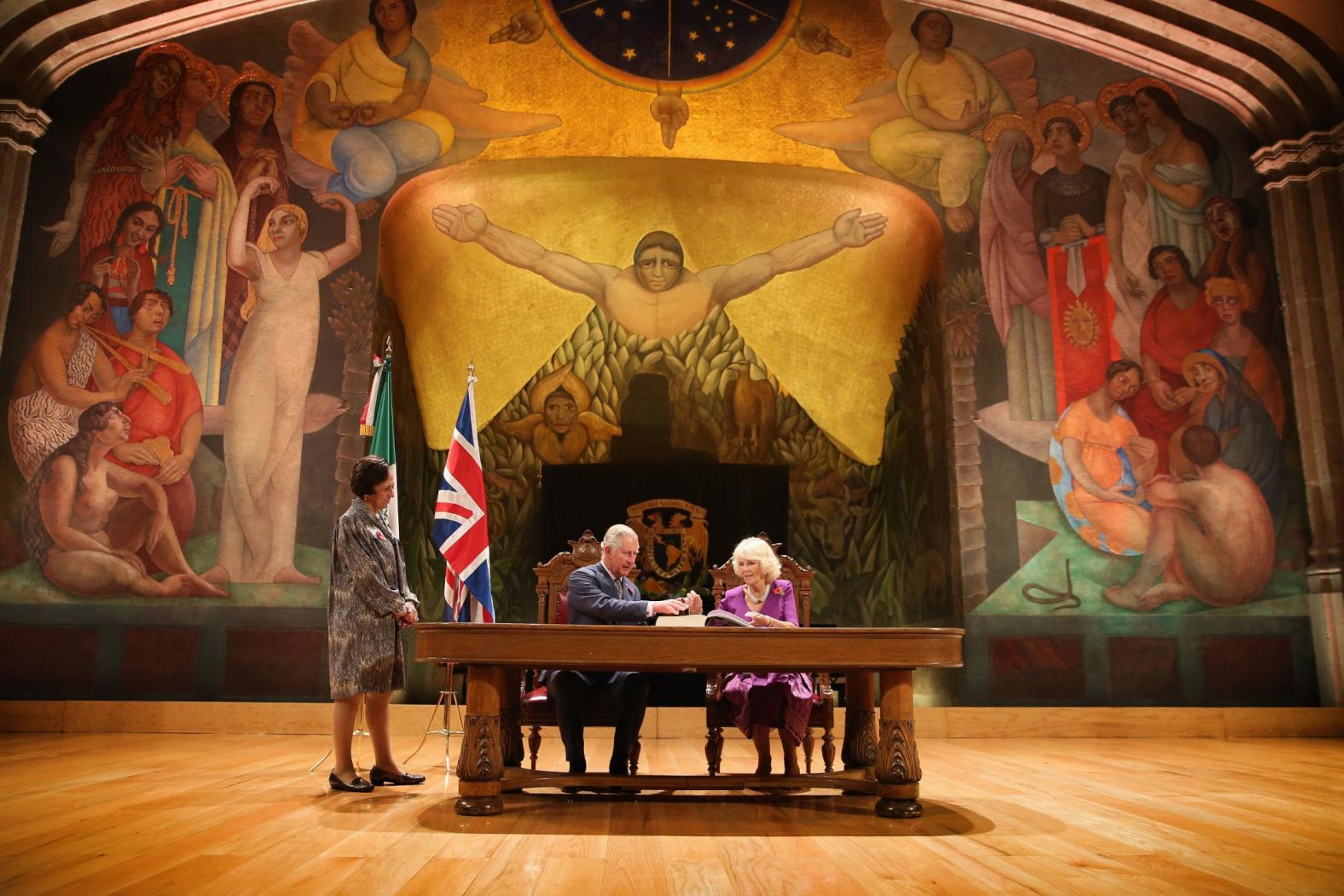 Charles and Camilla sign the visitor's book in front of a Diego Rivera mural while visiting Mexico City in November 2014.