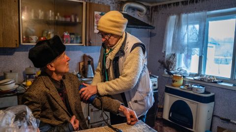 Schwez checks the blood pressure of 83-year-old Ivan Sotnykov at his home in Trokhizbenka.