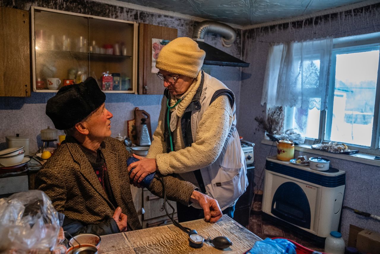 Schwez checks the blood pressure of 83-year-old Ivan Sotnykov at his home in Trokhizbenka.