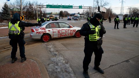 Police clear protesters and their vehicles from a blockade at the entrance to the Ambassador Bridge Saturday morning in Windsor, Canada. 