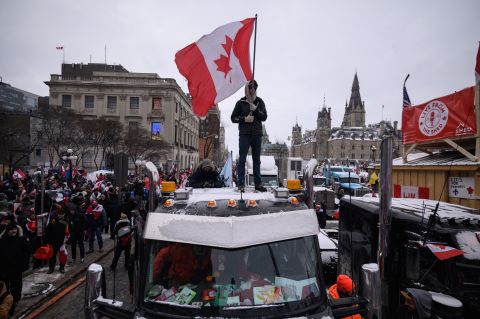 A demonstrator stands atop a truck holding a Canadian flag during a protest outside the Canadian Parliament in Ottawa on Saturday, February 12.